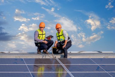 Çatıda yürüyen mühendisler ekipman kutusu ve telsiz iletişimiyle güneş hücresi panelini inceler ve kontrol ederler. Güneş pili akıllı ızgara ekolojik enerji alternatif enerji güneş ışığı enerji fabrikası konseptidir..