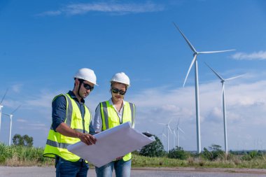 Üniforma giyen mühendis, kask teftişi ve rüzgar güneş pili panelinde elektrik enerjisi üretmek için araştırma yapıyor. Yeşil ekolojik enerji üretimi rüzgar sürdürülebilir enerji kavramı.