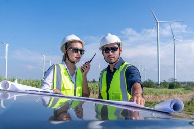 Üniforma giyen mühendis, kask teftişi ve rüzgar güneş pili panelinde elektrik enerjisi üretmek için araştırma yapıyor. Yeşil ekolojik enerji üretimi rüzgar sürdürülebilir enerji kavramı.