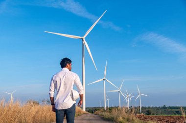 Üniforma giyen mühendis, kask teftişi ve rüzgar güneş pili panelinde elektrik enerjisi üretmek için araştırma yapıyor. Yeşil ekolojik enerji üretimi rüzgar sürdürülebilir enerji kavramı.