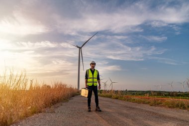 Üniforma giyen mühendis, kask teftişi ve rüzgar güneş pili panelinde elektrik enerjisi üretmek için araştırma yapıyor. Yeşil ekolojik enerji üretimi rüzgar sürdürülebilir enerji kavramı.