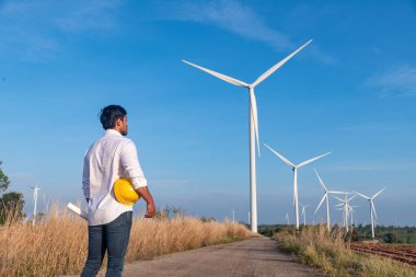 Üniforma giyen mühendis, kask teftişi ve rüzgar güneş pili panelinde elektrik enerjisi üretmek için araştırma yapıyor. Yeşil ekolojik enerji üretimi rüzgar sürdürülebilir enerji kavramı.