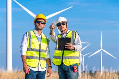 Üniforma giyen mühendis, kask teftişi ve rüzgar güneş pili panelinde elektrik enerjisi üretmek için araştırma yapıyor. Yeşil ekolojik enerji üretimi rüzgar sürdürülebilir enerji kavramı.