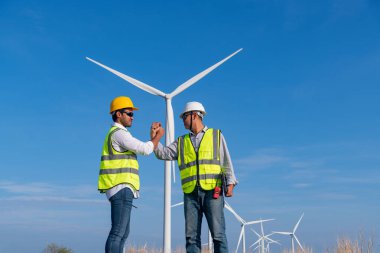 Üniforma giyen mühendis, kask teftişi ve rüzgar güneş pili panelinde elektrik enerjisi üretmek için araştırma yapıyor. Yeşil ekolojik enerji üretimi rüzgar sürdürülebilir enerji kavramı.