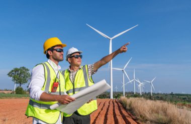 Üniforma giyen mühendis, kask teftişi ve rüzgar güneş pili panelinde elektrik enerjisi üretmek için araştırma yapıyor. Yeşil ekolojik enerji üretimi rüzgar sürdürülebilir enerji kavramı.