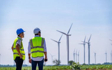 Üniforma giyen mühendis, kask teftişi ve rüzgar güneş pili panelinde elektrik enerjisi üretmek için araştırma yapıyor. Yeşil ekolojik enerji üretimi rüzgar sürdürülebilir enerji kavramı.