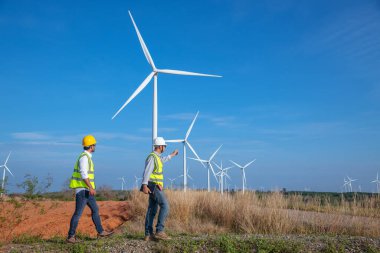 Üniforma giyen mühendis, kask teftişi ve rüzgar güneş pili panelinde elektrik enerjisi üretmek için araştırma yapıyor. Yeşil ekolojik enerji üretimi rüzgar sürdürülebilir enerji kavramı.