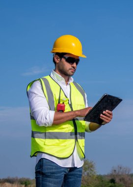 Üniforma giyen mühendis, kask teftişi ve rüzgar güneş pili panelinde elektrik enerjisi üretmek için araştırma yapıyor. Yeşil ekolojik enerji üretimi rüzgar sürdürülebilir enerji kavramı.