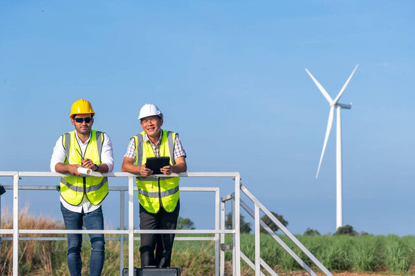 Engineer wearing uniform ,helmet inspection and survey work in wind solar cell panel to generate electricity energy. Green ecological power energy generation wind sustainable energy concept.