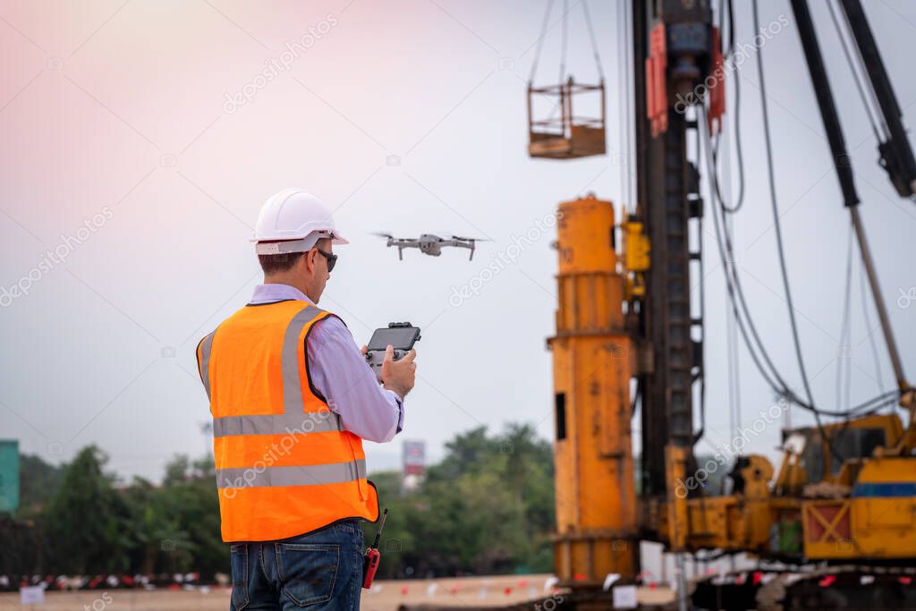 Construction engineer wear safety uniform under inspection and survey workplace by tablet with excavation truck digging and worker construction road background