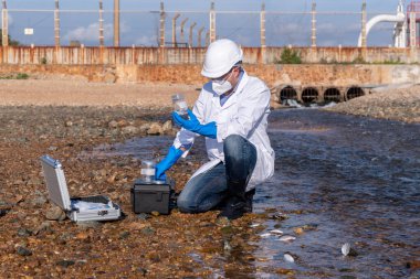 Çalışan su analizi ve su kalitesi altında koruyucu üniforma ve eldiven giyen bilim adamları laboratuvardaki vakayı kontrol etmek için atık su getirerek çevre kirliliği sorunu kavramı