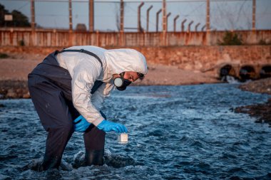 Çalışan su analizi ve su kalitesi altında koruyucu üniforma ve eldiven giyen bilim adamları laboratuvardaki vakayı kontrol etmek için atık su getirerek çevre kirliliği sorunu kavramı