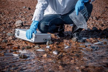 Çalışan su analizi ve su kalitesi altında koruyucu üniforma ve eldiven giyen bilim adamları laboratuvardaki vakayı kontrol etmek için atık su getirerek çevre kirliliği sorunu kavramı