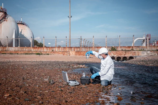 scientist wearing protective  uniform and glove under working water analysis and water quality by get waste water to check case in laboratory is environment pollution problem concept