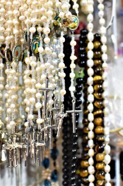 Katolik dükkanında gümüş haçlı beyaz tespihler ve dini mücevherler sergileniyor.