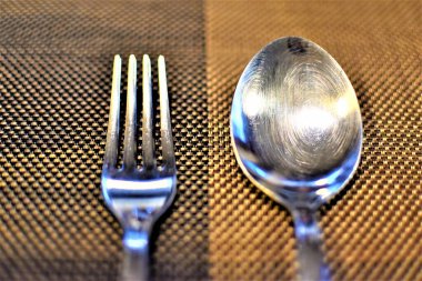 Restoran masasına yerleştirilmiş metal çatal ve kaşığın yüksek açılı görüntüsü.