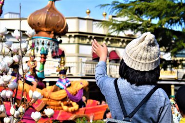 Kalabalıktaki küçük bir kız lunaparktaki geçit töreninde sokak sanatçılarına el sallıyor.