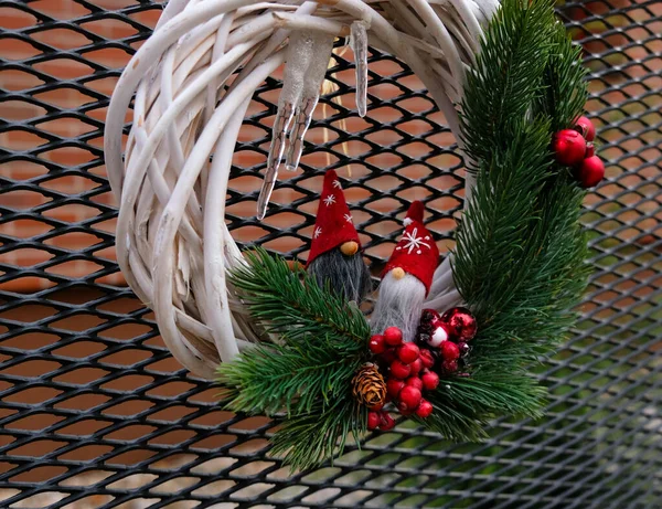 A grinalda de Natal decora-se com pequenos gnomos, um ramo de abeto com bagas vermelhas e icicles. Coroa decorativa tradicional de Natal cria um clima festivo em antecipação do feriado. — Fotografia de Stock