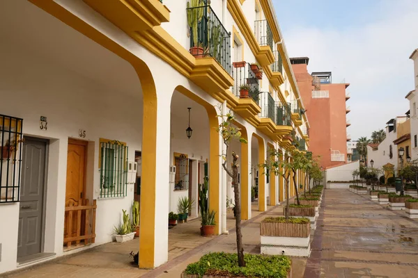 Kilátás a lakóépületre boltívvel. Apartman ablakokkal, erkéllyel és bejárattal, tipikus spanyol építészet. Zöld növényekkel teli sikátor az utcán. Torremolinos, Andalúzia, Spanyolország. — Stock Fotó