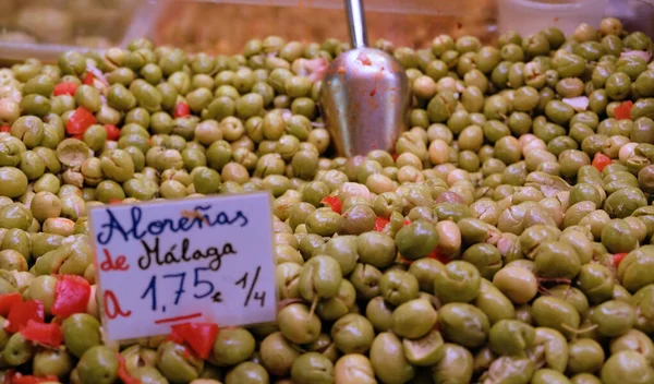 Színes olívabogyó közelkép a malagai termelői piacról. Ízletes fekete-zöld organikus erjesztett olajbogyó műanyag tartályban eladó, egészséges vegetáriánus élelmiszer háttér. — Stock Fotó