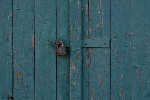 古色古香的蓝色木画大门的旧建筑.破旧的门板。老剥皮画的门，破碎。门上的铁锁生锈了.Threadbare Wooden rustic background. — 图库照片