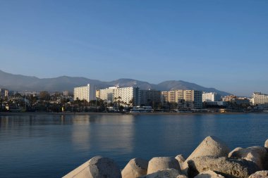 Malaga, Endülüs, İspanya 'daki Akdeniz kıyısındaki yüksek binalar ve otellerin manzarası. Kumsal manzarası, palmiye ağaçları, mavi deniz, mavi gökyüzü ve dağlar. Emlak kavramı.