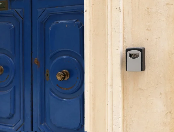 Smart key lock mounted on wall for renting apartment. Safe Key Box is used when the guest arrives at the touristic flat and the host can\'t open the door. Safe access to living space. Blue vintage door