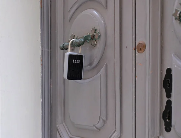 Smart key lock mounted on a gray door for renting apartment. Safe Key Box is used when the guest arrives at the touristic flat and the host can\'t open the door. Safe access to living space.