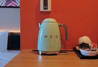 Green electric kettle SMEG for boiling water and making tea or coffee on table in hotel as design element. Household kitchen appliances for makes hot drinks. Moscow - July, 2022.