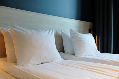 Close-up fragment of bedroom with empty bedside table, turn off reading lamp and a socket in modern interior design home or hotel. Soft pillow and blanket, stylish comfortable furniture.