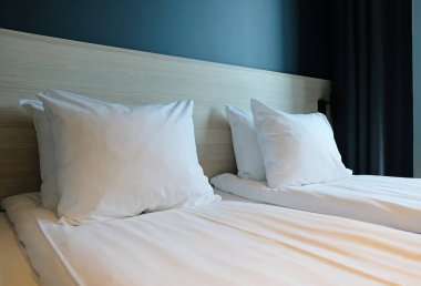 Close-up fragment of bedroom with empty bedside table, turn off reading lamp and a socket in modern interior design home or hotel. Soft pillow and blanket, stylish comfortable furniture.