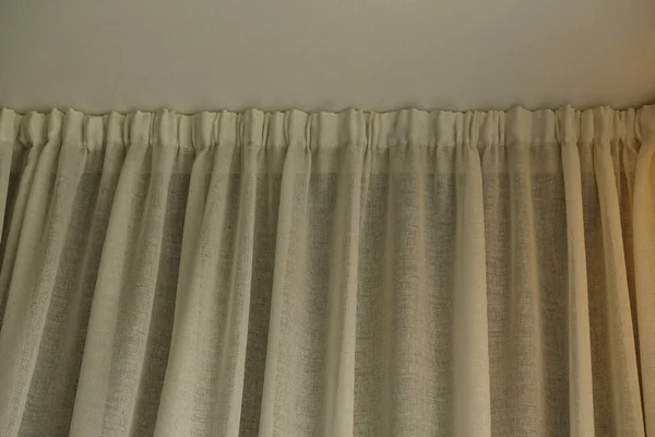 Close-up Cornice with drapes and white curtain or tulle. White wall, ceiling, cornice niche, curtains on the window. Corner hidden curtain rod. Interior details close up.