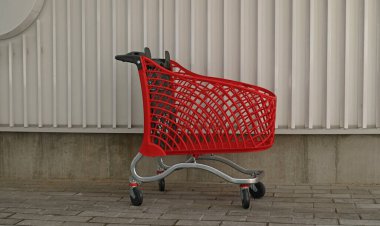 Endüstriyel duvar arka planında boş kırmızı alışveriş. Süpermarkette alışveriş arabası. İndirim, indirim, alışveriş, kara cuma, ekonomi konsepti. Tüketici toplumu eğilimi. Çevrimiçi Alışveriş Konsepti.