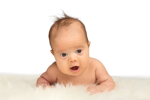 Smling nyfödd baby flicka liggande på magen på ett fårskinn — Stockfoto