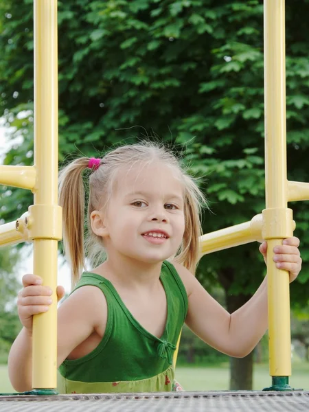 Uma jovem tenta chegar ao slide no parque infantil — Fotografia de Stock