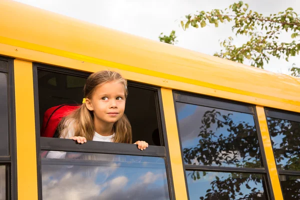 Liten flicka tittar ut en skolbuss-fönstret — Stockfoto