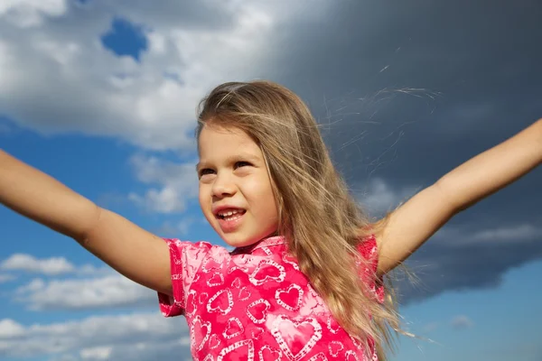 Возбужденная молодая девушка против облачного неба — стоковое фото
