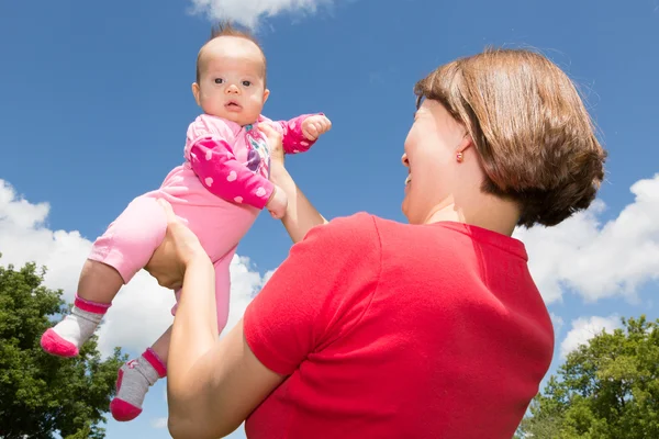 Mamma håller dottern baby högt upp i luften — Stockfoto