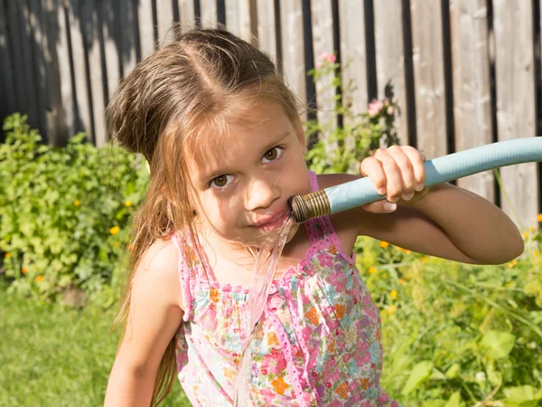 Flickan dricka från en slang — Stockfoto