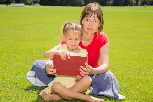 Een meisje en haar moeder met tablet pc — Stockfoto