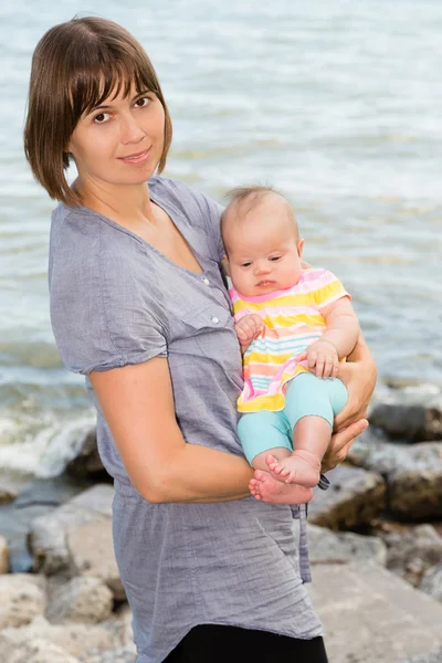 Matka a její dcera dítě na břehu moře — Stock fotografie