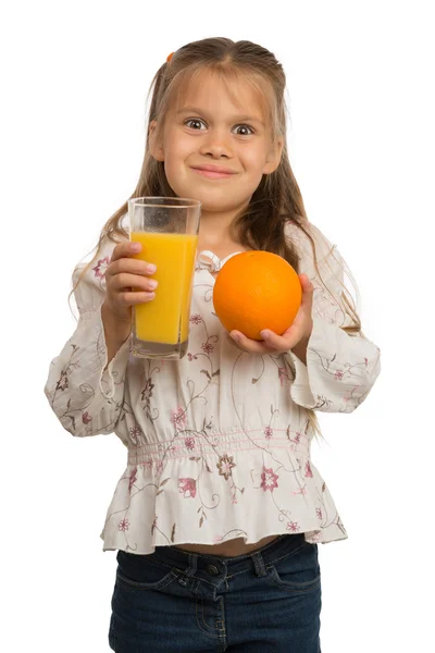 Menina segura um copo com um suco de laranja com uma mão e — Fotografia de Stock