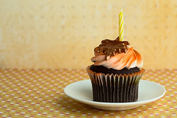 Cupcake auf einer Untertasse mit Kerze — Stockfoto