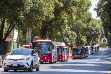 Roma, İtalya. 29 Haziran 2022: Roma 'da Villa Borghese' nin ağaçlandırılmış caddesindeki şehir merkezine park edilmiş şehir ve turist taşımacılığı otobüsleri. Ön sırada bir taksi var..