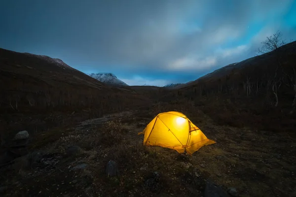 Светящийся жёлтый шатёр и облака в горах Хибин осенней ночью. Россия — стоковое фото