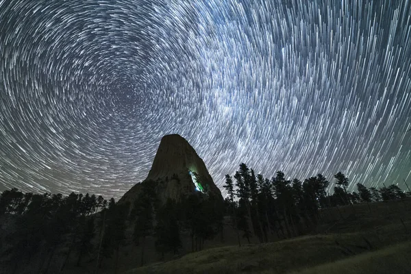 Gece vakti Şeytan Kulesi 'nin üzerindeki Yıldız Yolları. Duvarda hafif bir dağcı fişeği. Wyoming, ABD