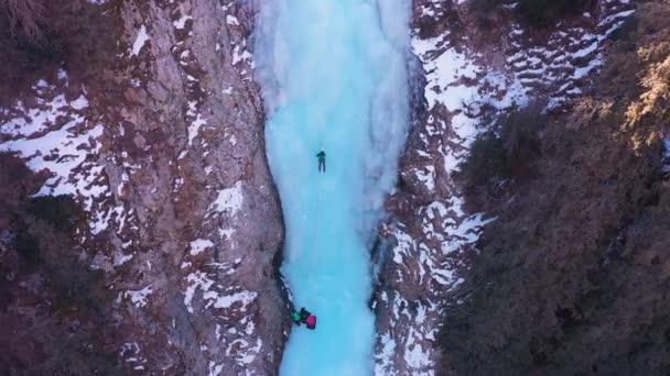 Der Mensch führt auf dem Eis. Eisklettern auf gefrorenem Wasserfall — Stockvideo