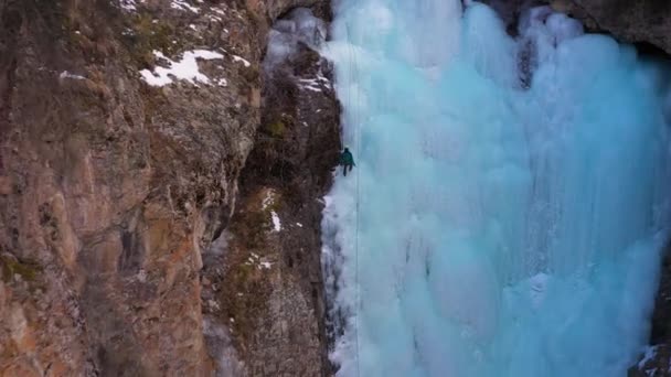 男は降下してる。凍った滝で氷のクライミング。空中展望 — ストック動画