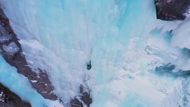 Człowiek prowadzi na lodzie. Wspinaczka po lodowatym wodospadzie. Widok z powietrza — Wideo stockowe