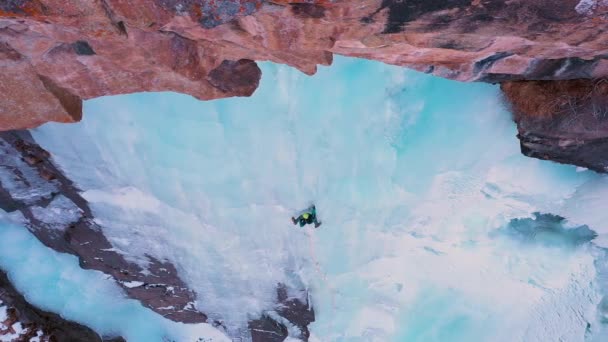 Человек лидирует на льду. Восхождение на ледяной водопад. Вид с воздуха — стоковое видео